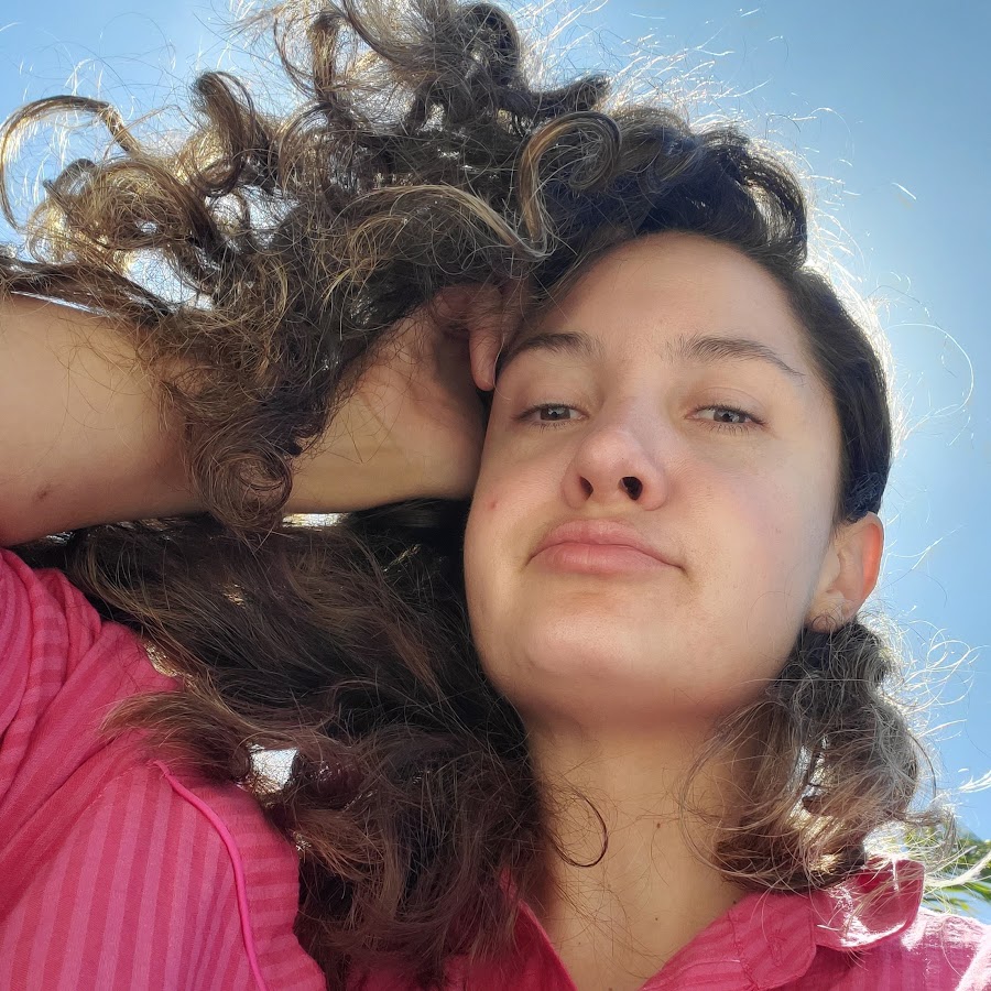 Lauren's face looking forward at the camera, with large black headphones around her neck.