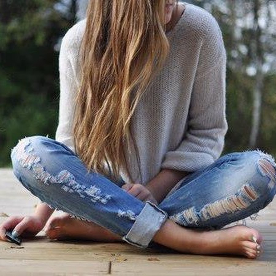 Девушка в рваных джинсах сидит